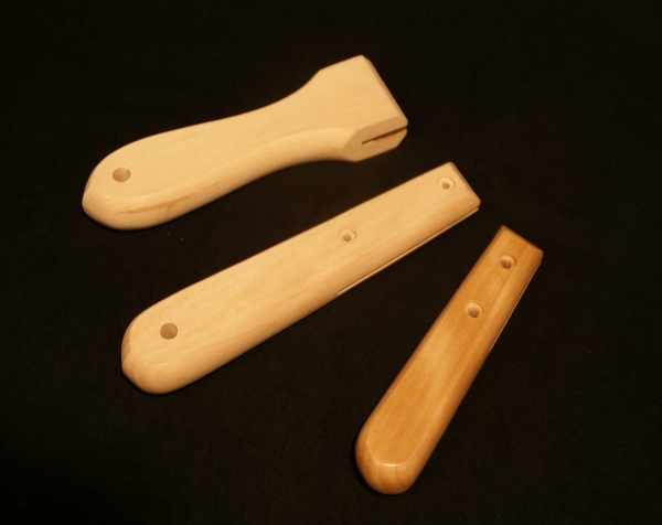 Three flat custom wooden handles showing a variety of secondary operations such as cross bore holes and slotted ends.